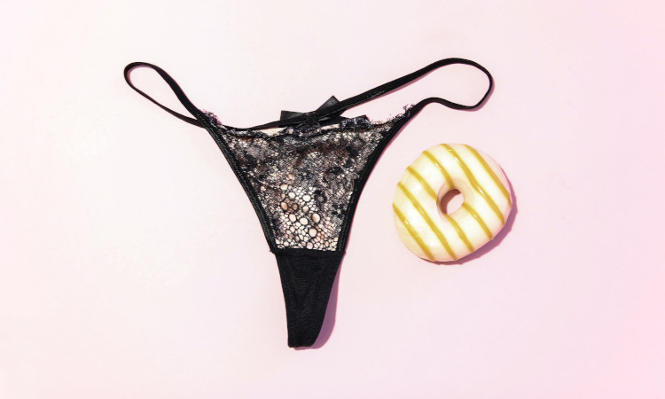 Calcinha preta de renda com donut ao lado a ilustrar fetiche por calcinha usada.
