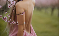 Costas de modelo ficha rosa ciom flores rosas em cima de seu braço e costas desnudas.
